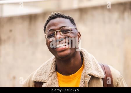 Close up portrait of african american teenage boy looking at camera smiling and laughing at univesity campus. Smart young student standing outdoors at Stock Photo
