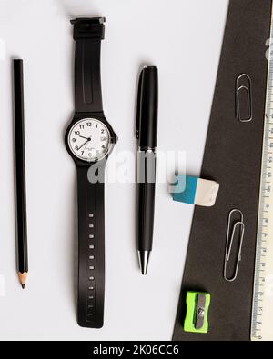 Pen, pencil, eraser, pencil sharpener, wristwatch and ruler on a contrasting black and white background Stock Photo