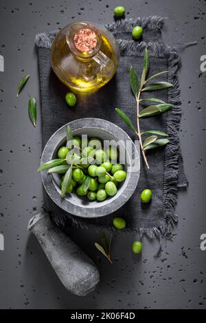 Healthy and fresh raw olives with mortar and a twig. Freshly picked green olives. Stock Photo