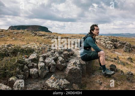 Chinese male trail runner sitting on rock Stock Photo