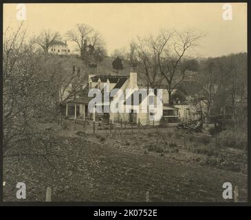 Old Dunbar quarters, Falmouth, old building from hillside, between 1925 and 1929. Photograph shows a view, from beyond a garden, of a clapboard-sided building with three dormers, large chimneys at each end, a porch off the front, and a small shed, inside a fenced-in yard. Also shows a large house on a hill in the background. Stock Photo