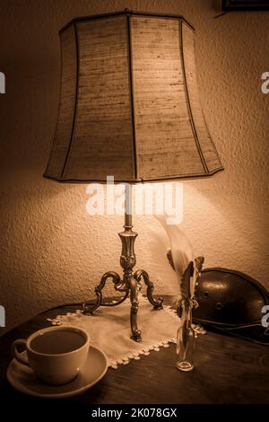 Lamp on table with coffee, feather, leather helmet, sepia colour, black and white, Ulm, Germany Stock Photo