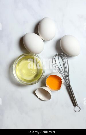 Egg whites in small bowls and egg yolks in egg shells Stock Photo