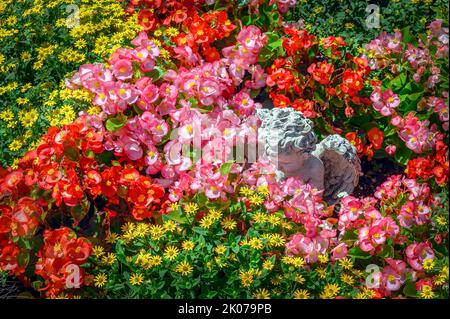 Flowering with busy lily (impatiens walleriana) and ceramic putti on cemetery in Fischen, Allgaeu, Bavaria, Germany Stock Photo