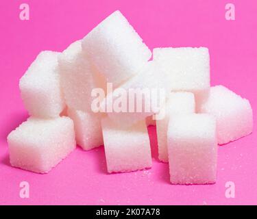 Sugar cubes isolated on pink background. Close-up of pile of sugar cubes. Sweet food idea concept. Stock Photo