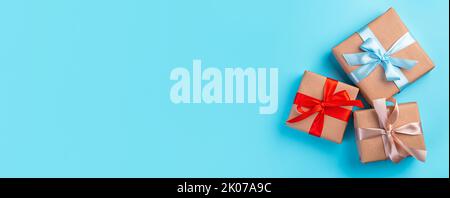 Three gift boxes with colored ribbons on a blue background. Stock Photo