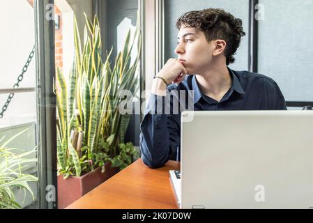 Young thoughtful man in the office looking through the window Stock Photo