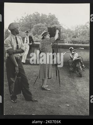Photographer Frances Benjamin Johnston standing beside her view camera preparing to take a photograph Biltmore Estate; her assistant Huntley Ruff is in the foreground and a motorbike is in the background, 1938. Stock Photo