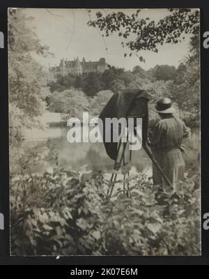 Photographer Frances Benjamin Johnston standing beside her large view camera looking towards the Biltmore Estate mansion in the background, c1938. Stock Photo