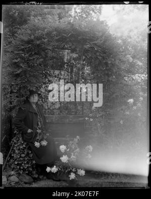 Frances Benjamin Johnston, photographer, posed sitting with peonies in the garden at &quot;Auld Lang Syne,&quot; James Herndon Lightfoot house, Takoma Park, Maryland, 1938. Stock Photo