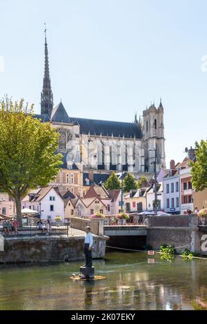 Notre-Dame d'Amiens cathedral overlooks the Somme river, with the 'Man on buoy' statue by Stephan Balkenhol in the foreground, on a sunny summer day. Stock Photo