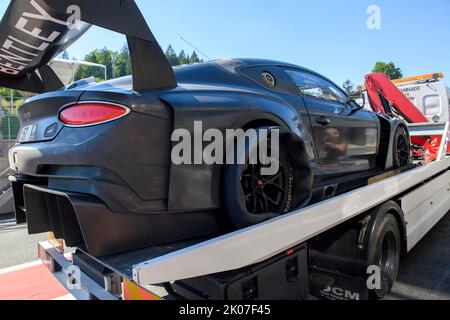 Bentley GT3 race car is taken back to Pit Lane of circuit by tow truck with punctured right rear tyre, FIA Formula One circuit, Circuit de Spa Stock Photo