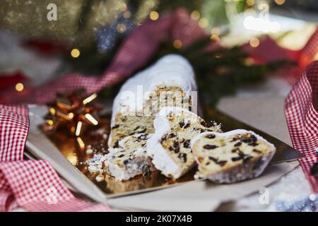 Christmas stollen on reflection paper background. Traditional Christmas festive pastry dessert. Christmas tradition with bokeh background. Festive bac Stock Photo