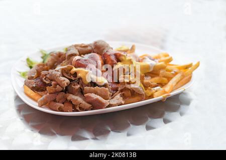 Doner kebab with French fries and various sauces on a plate, popular fast food from Turkish cuisine, copy space, selected focus, narrow depth of field Stock Photo