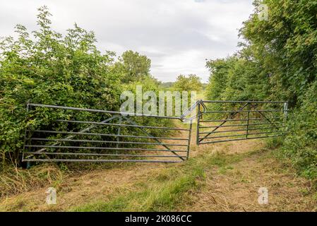 Metal bar gates, uneven, chained, closed shut. Stock Photo