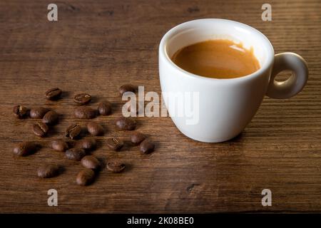 White cup of espresso with coffee beans on wooden background Stock Photo