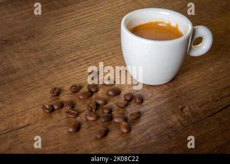 White cup of espresso with coffee beans on wooden background Stock Photo