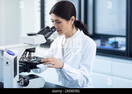Chinese scientist looking through a microscope Stock Photo