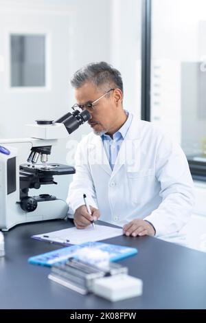 Chinese scientist looking through a microscope Stock Photo