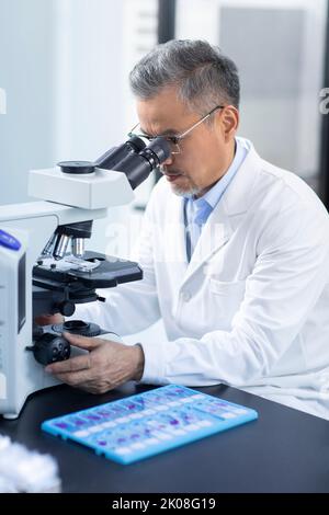 Chinese scientist looking through a microscope Stock Photo