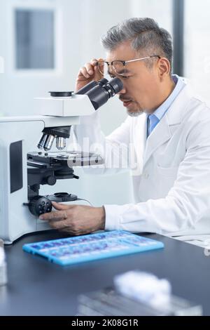 Chinese scientist looking through a microscope Stock Photo