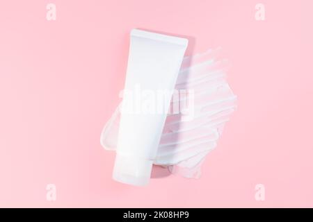White squeeze bottle plastic tube and moisturizer smear texture on pink background. flat lay, top view. Daily moisturizing cream, gel, skin care, suns Stock Photo