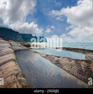 Stony beach with tidal baths at Ersfjord, Senja, Norway. Summer polar day night coast. The dragon teeth rock in far. Stock Photo