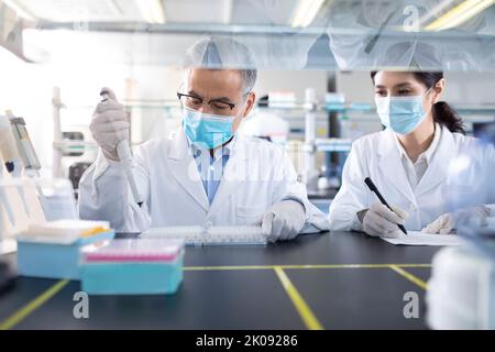 Chinese scientists examining medical sample in laboratory Stock Photo