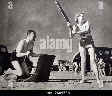 Couple playing cricket on the beach during summer holiday. Illustrated news cutting. Stock Photo