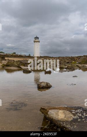 A view of the historic Southerness Lighthouse in Scotland with reflections in tidal pools in the foreground Stock Photo