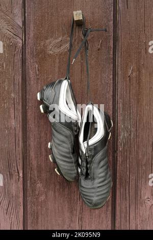 A pair of soccer boots hanging on a wooden wall. The end of the football career Stock Photo