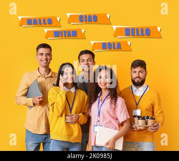 Team of young workers and words HELLO in different languages on yellow background Stock Photo