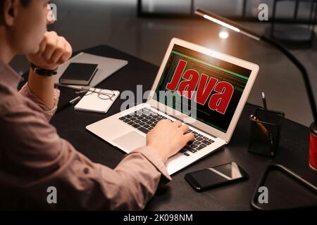 Male programmer writing Java program in office at night Stock Photo