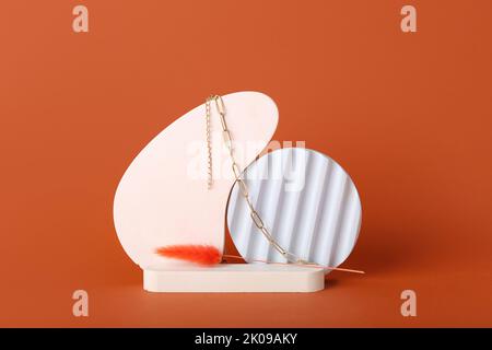 Showcase pedestal, floral decor and necklace on brown background Stock Photo