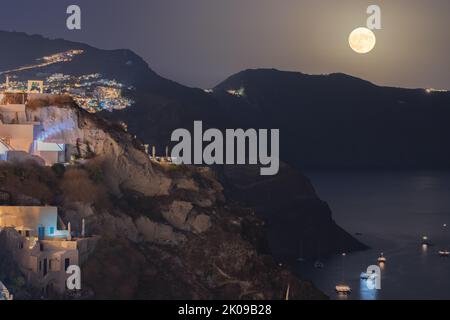 Dramatic full harvest moon rise over the caldera and Greek Island of Santorini on September 10, 2022 taken from the coastal village of Oia in Greece. Stock Photo