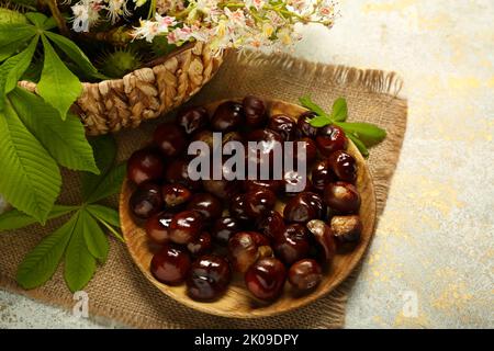 Plate with fresh chestnuts on light background Stock Photo