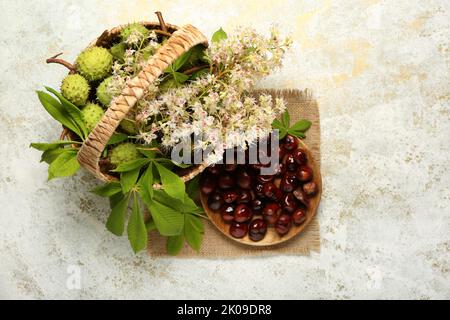 Composition with fresh chestnuts, flowers and leaves on light background Stock Photo