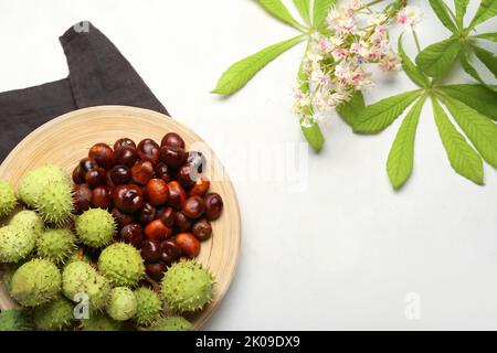 Plate with fresh chestnuts on light background Stock Photo