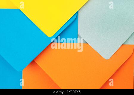 Orange, blue, yellow and silver envelopes forming a modern geometric pattern. Abstract postal backdrop design, close up. Stock Photo