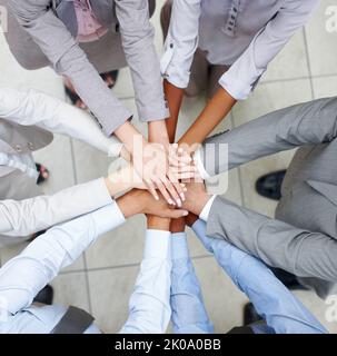 Team merging. Merged colleagues put their hands together to celebrate their unity. Stock Photo