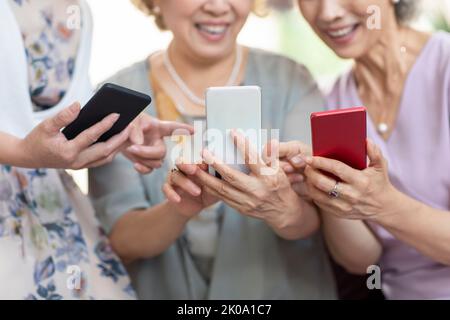 Happy senior Chinese friends using smart phones at home Stock Photo