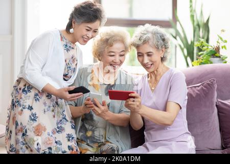 Happy senior Chinese friends using smart phones at home Stock Photo