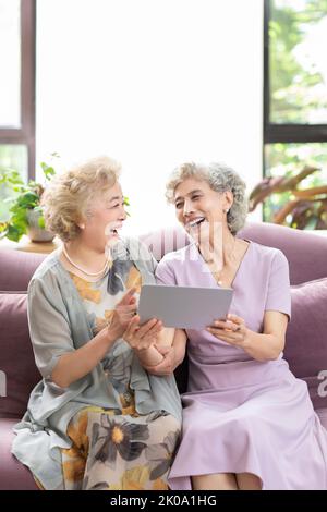Happy senior Chinese friends using digital tablet at home Stock Photo