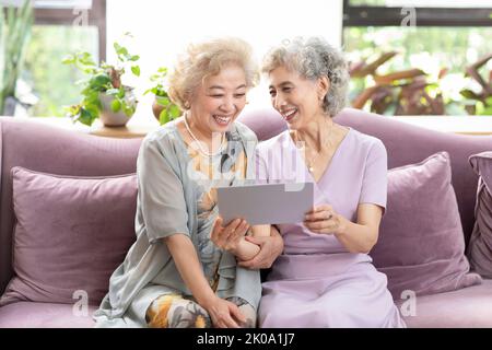 Happy senior Chinese friends using digital tablet at home Stock Photo