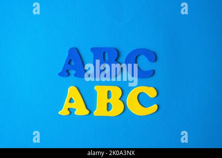 Blue and yellow letters of the alphabet on a blue background. The concept of learning languages Stock Photo