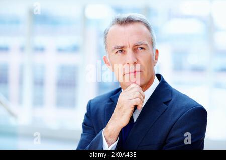 Executive deep in thought. Business man with hand on chin, looking off into distance. Stock Photo