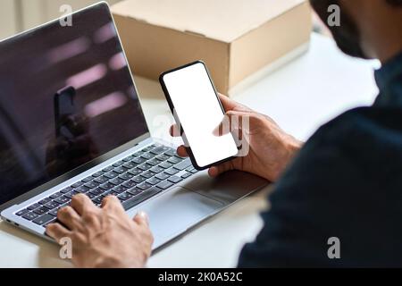Business man holding smartphone with mock up screen at work desk. Stock Photo