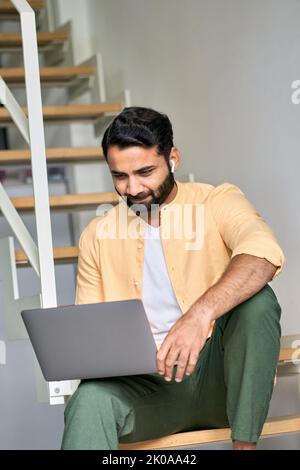 Indian man user sitting at home using laptop remote working, vertical. Stock Photo