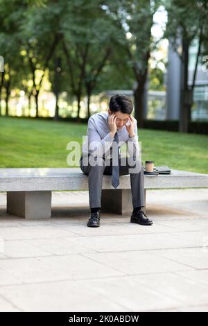 Young Chinese businessman having a headache Stock Photo