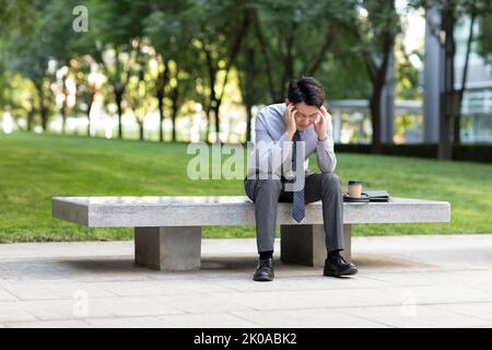 Young Chinese businessman having a headache Stock Photo